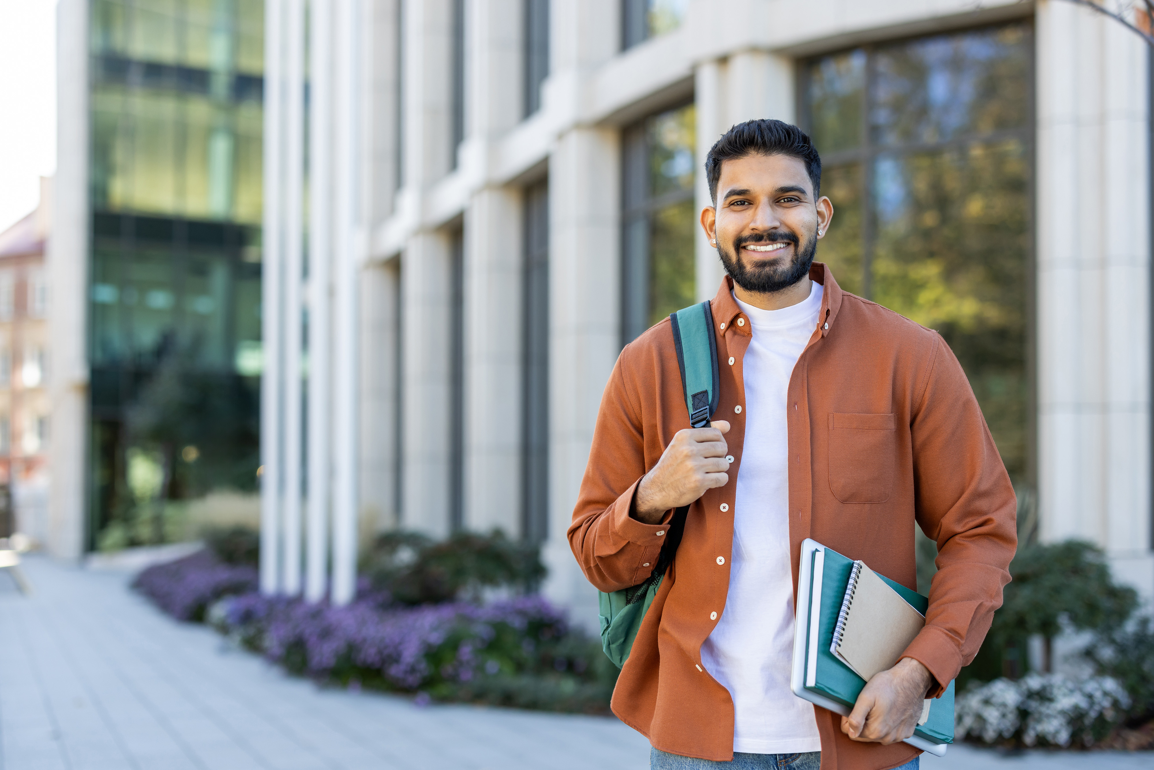 A smiling male student stands in front of a building.