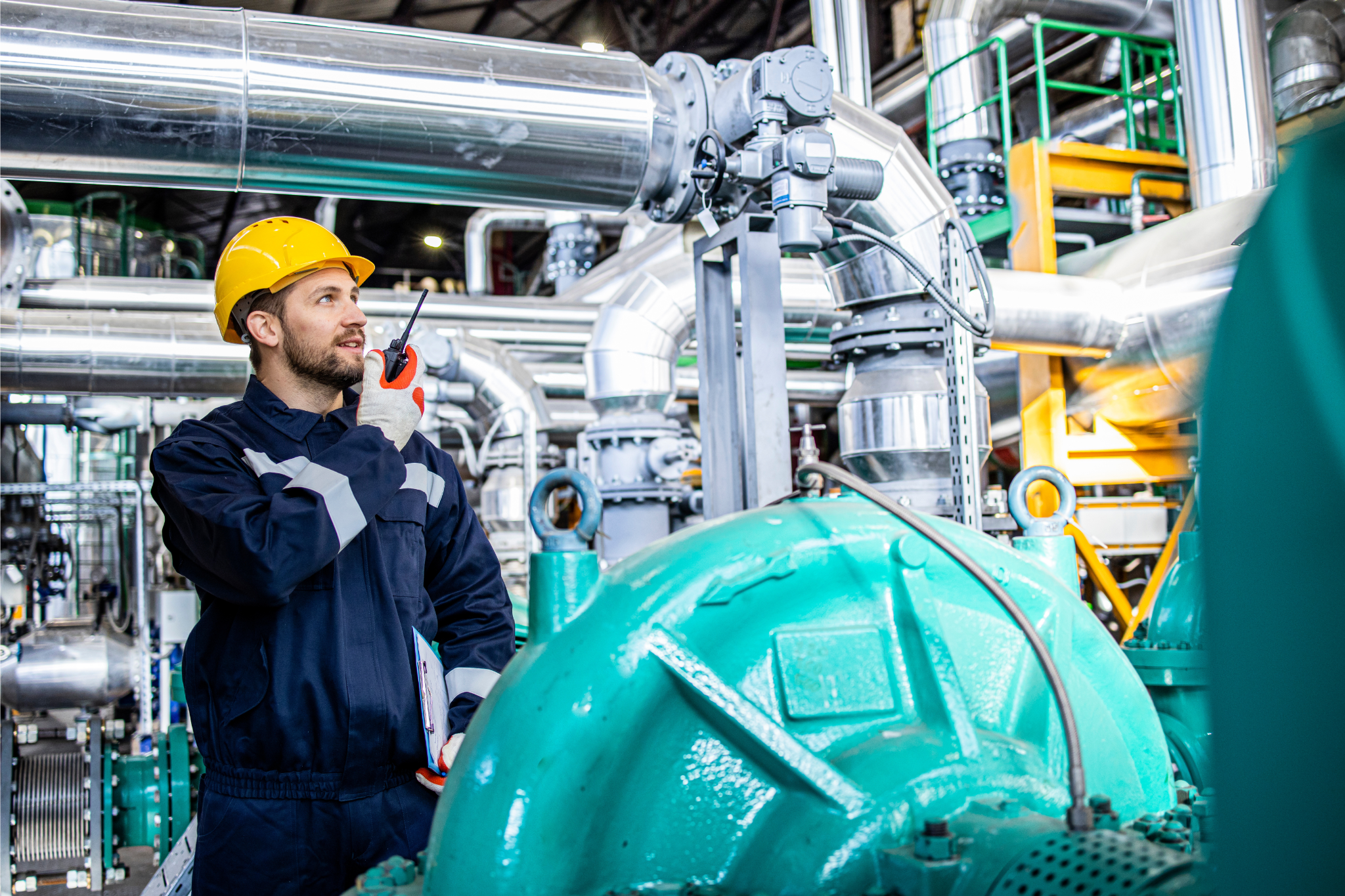 Techniker in Schutzkleidung prüft industrielle Anlage.
