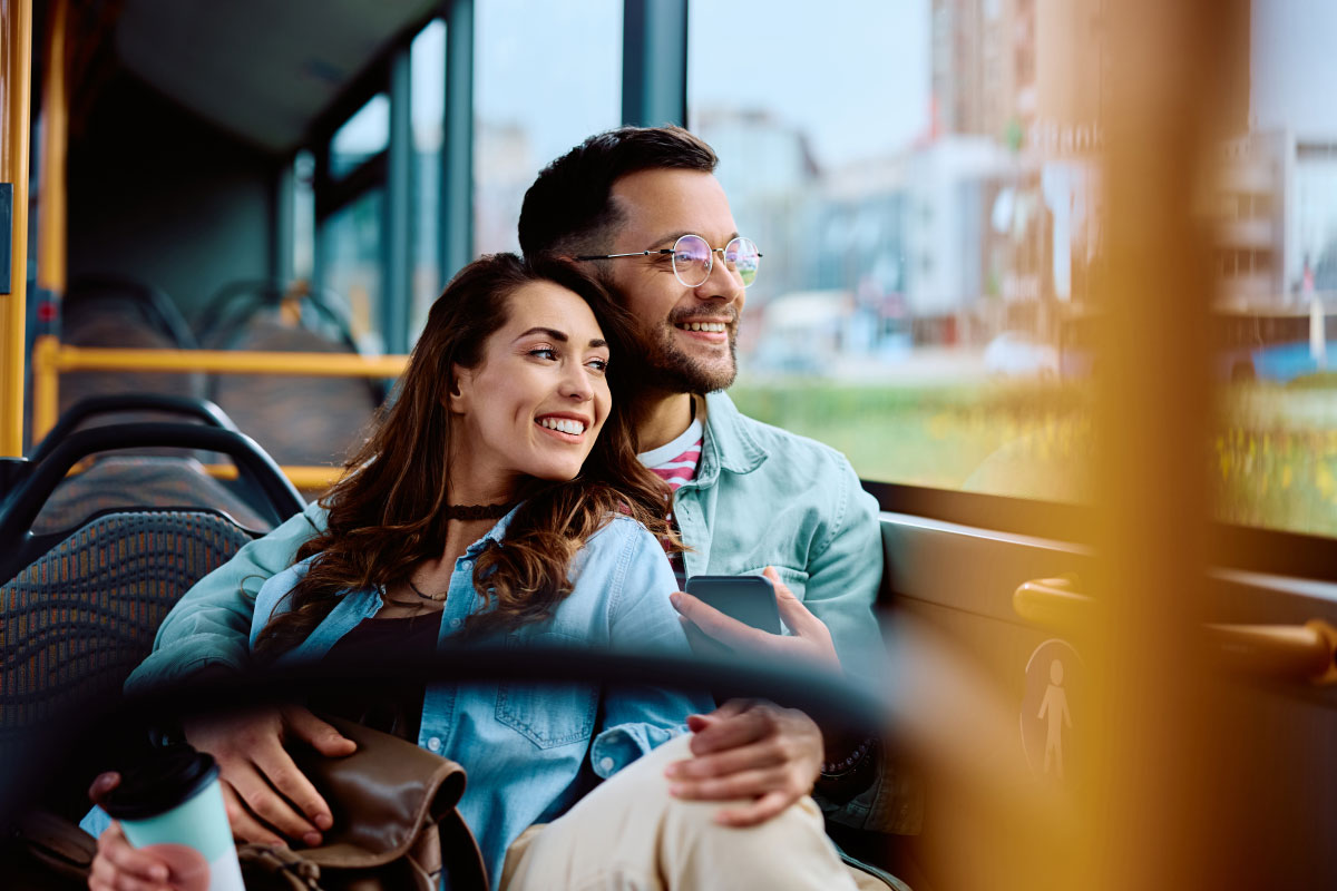 Fahrgäste im Bus mit Smartphone und Kaffeebecher
