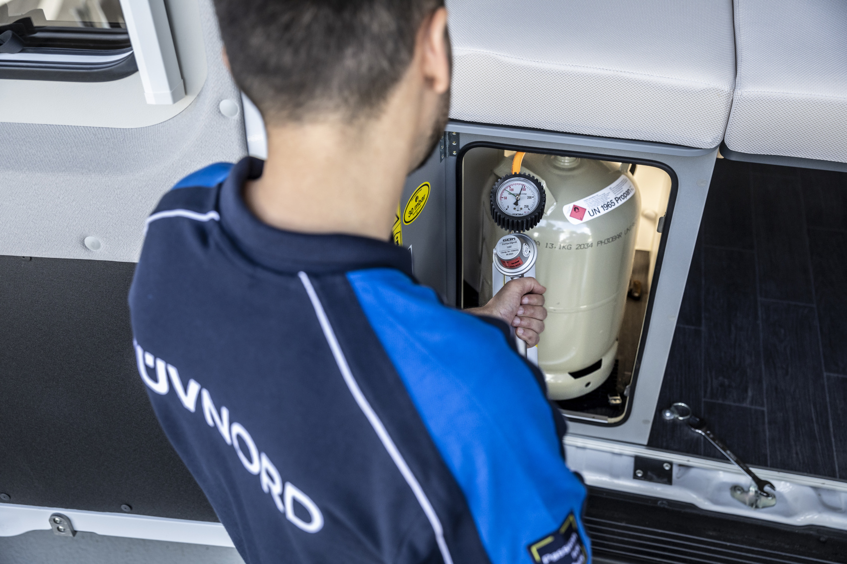 Prüfingenieur überprüft Gasflasche in einem Wohnmobil