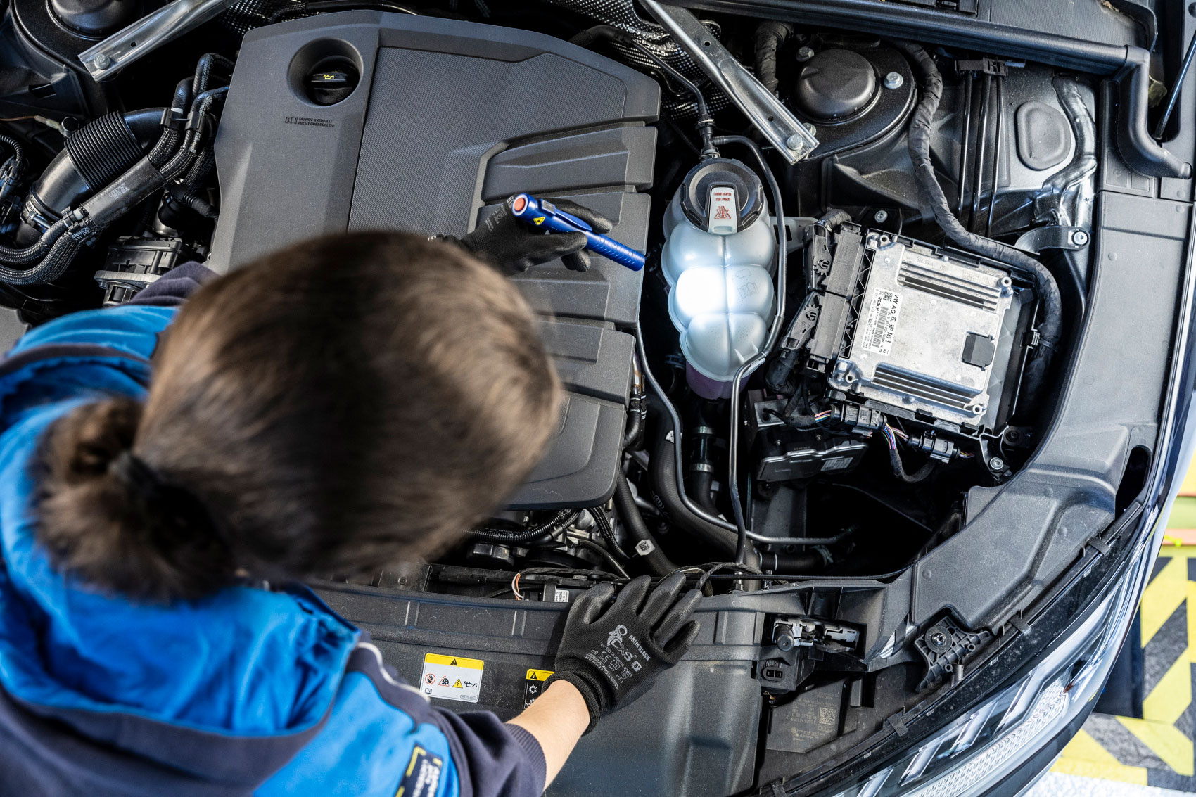 Prüfingenieurin bei der Motorinspektion eines Fahrzeugs an der TÜV NORD Station
