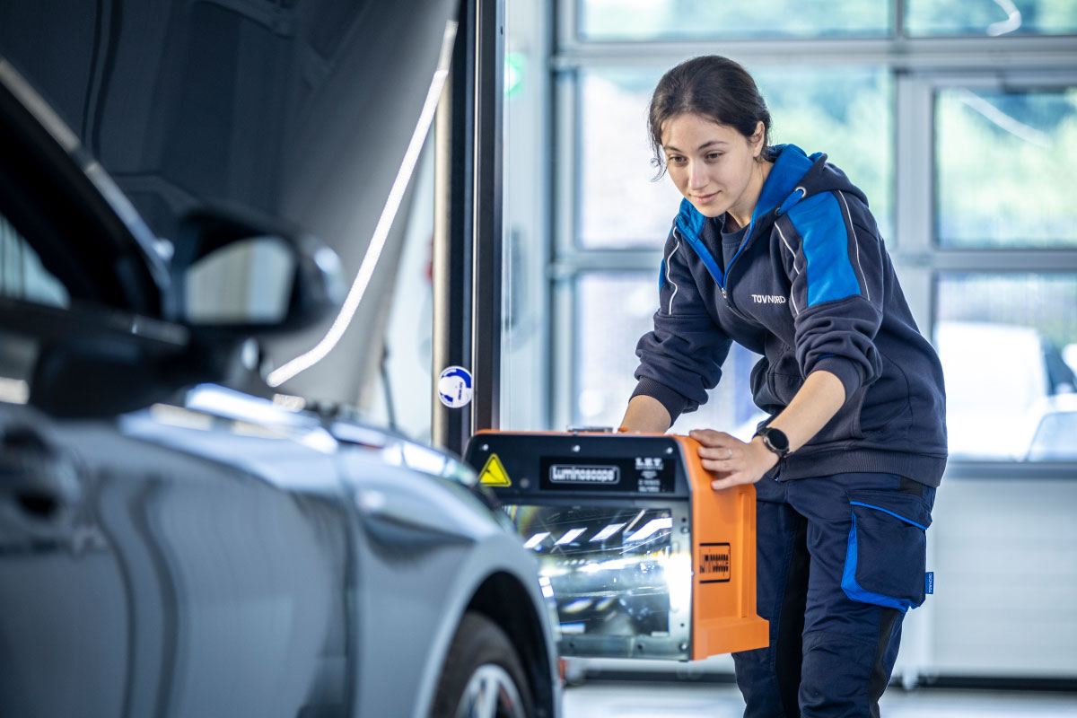 Prüfingenieurin bei der Scheinwerferprüfung an einem Fahrzeug an der TÜV NORD Station