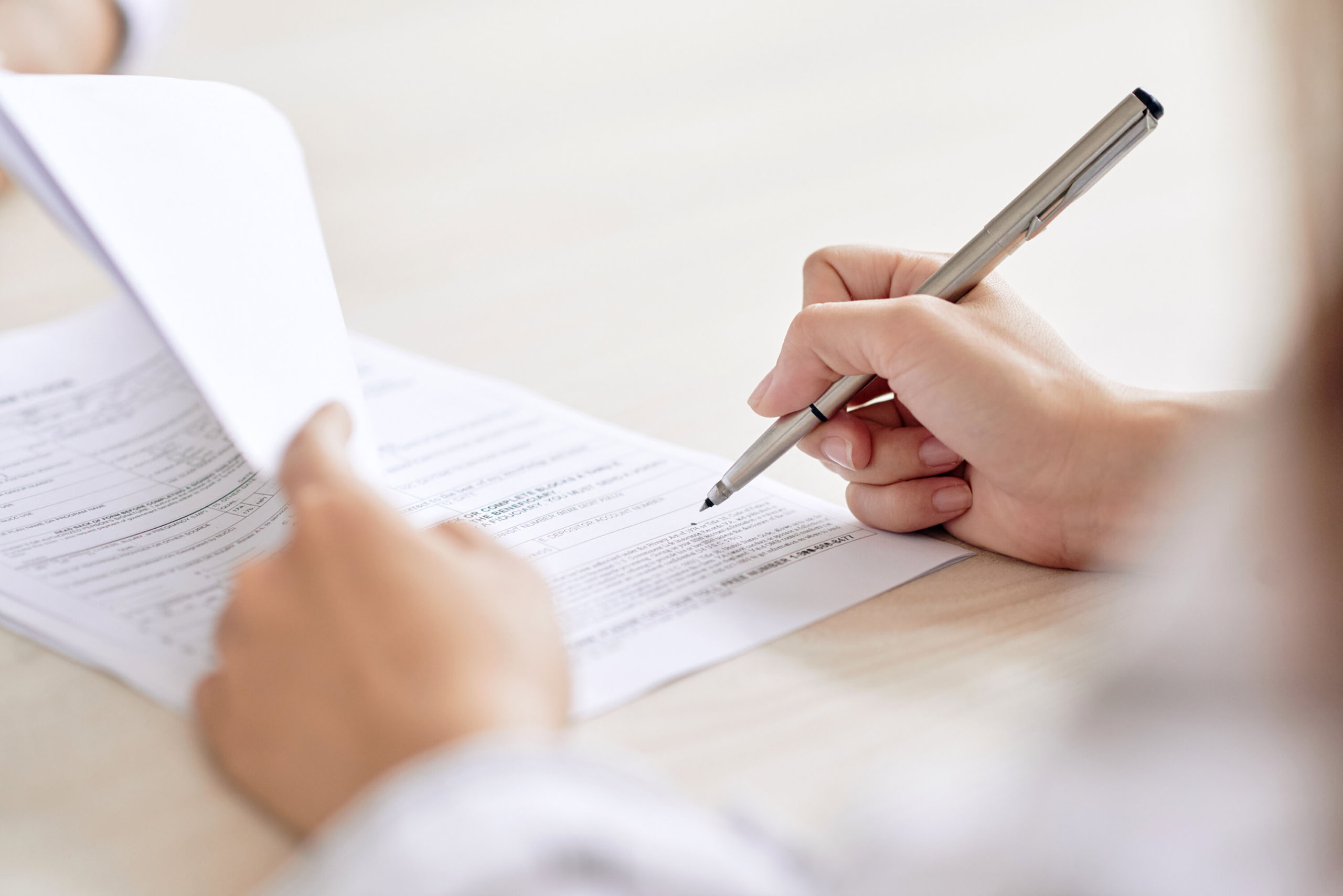 Nahaufnahme einer Hand, die einen Stift über ein Formular führt