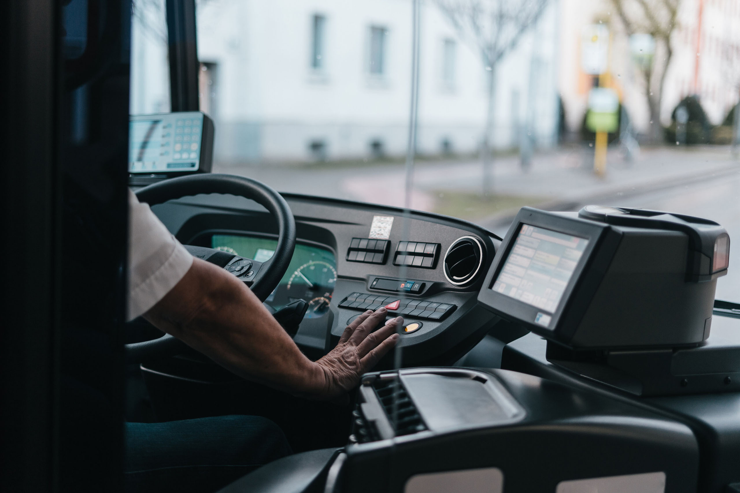 Busfahrer bedient Armaturenbrett und Fahrkartenautomat in einem modernen Linienbus