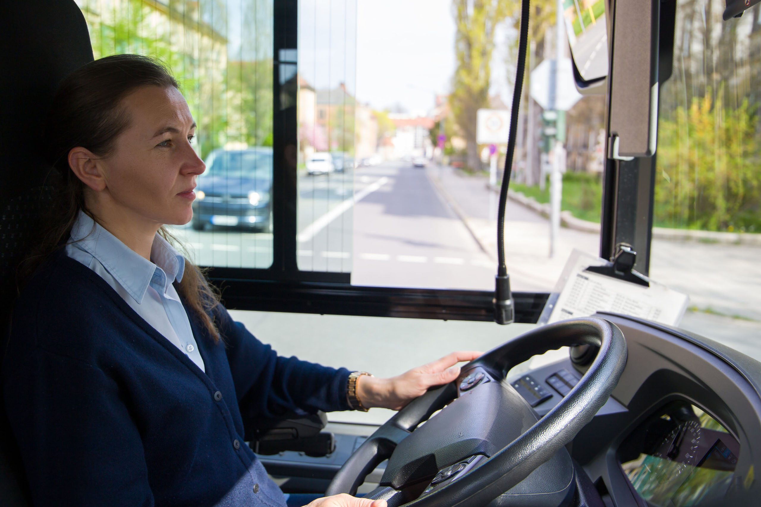 Frau fährt einen Bus und schaut auf die Straße aus dem Fenster