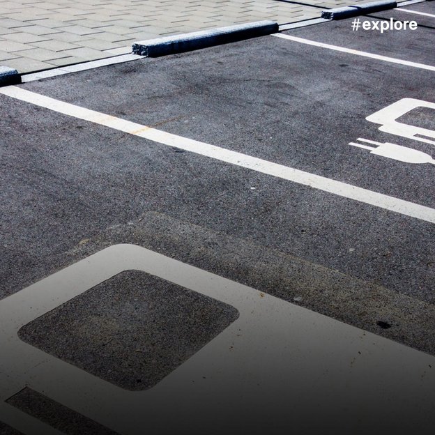 Speziell gekennzeichnete Parkplätze für Elektrofahrzeuge mit weißen Markierungen auf dunklem Asphalt. Die Stellplätze sind mit Elektroauto-Symbolen markiert und durch weiße Linien voneinander abgegrenzt.