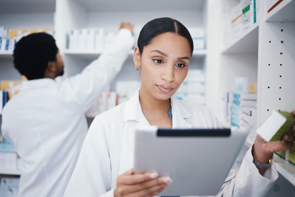 Apothekerin prüft Informationen auf einem Tablet in einer modern eingerichteten Apotheke.