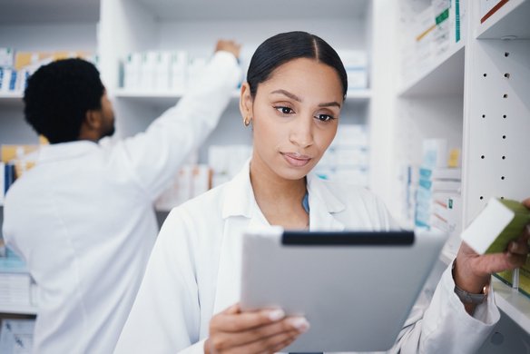 Apothekerin prüft Informationen auf einem Tablet in einer modern eingerichteten Apotheke.