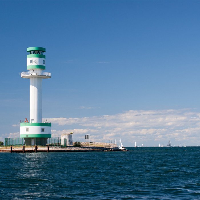 Leuchtturm in Kiel an der Ostsee mit Segelbooten und blauem Himmel