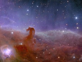 Eine spektakuläre astronomische Aufnahme eines Nebels mit rötlich-orangefarbenen Wolkenformationen vor einem dunkelblauen Sternenhimmel. Der Nebel erinnert an eine pferdekopfartige Struktur