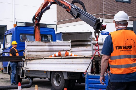 Arbeiter in Sicherheitskleidung bedient einen LKW-Ladekran bei einer Schulung.
