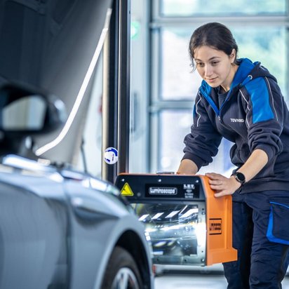Lichttest von einer Frau in TÜV NORD Kleidung in einer Werkstatt