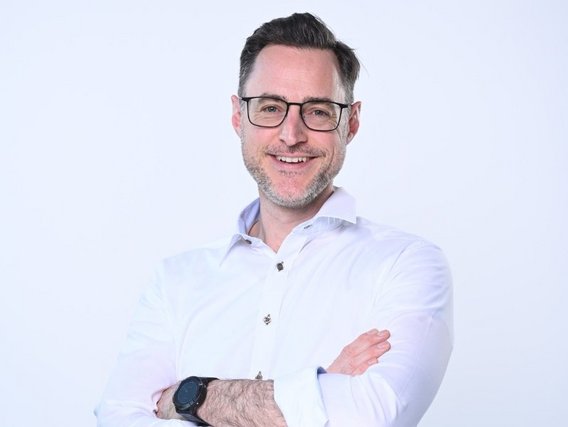 Roman Meier-Andrae mit Brille und weißem Hemd, die Arme verschränkt.