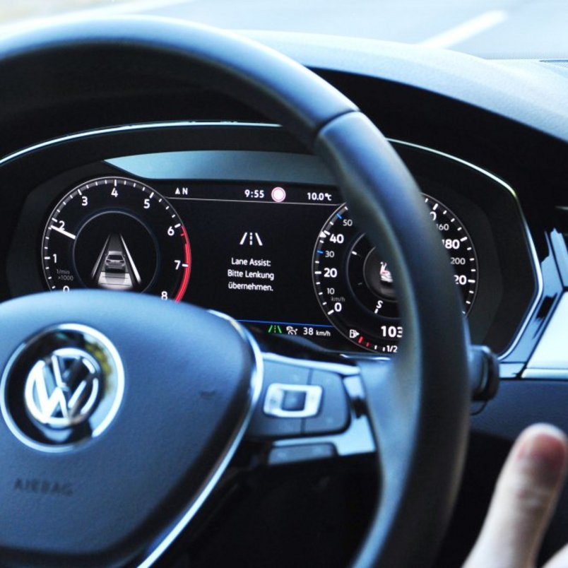 Fahrzeugcockpit mit aktivem Spurhalteassistent‑Display, Hände bewusst nicht am Lenkrad, Fokus auf teilautomatisierte Fahrfunktion