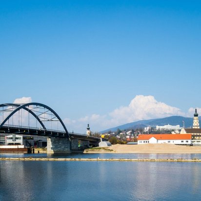 Blick auf die Brücke und die Stadt Deggendorf mit dem historischen Stadtturm und den umliegenden Bergen