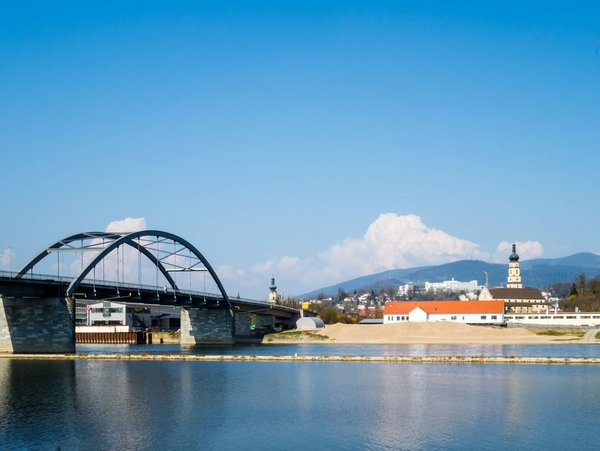 Blick auf die Brücke und die Stadt Deggendorf mit dem historischen Stadtturm und den umliegenden Bergen