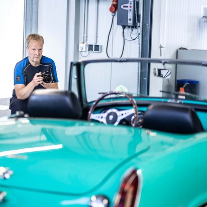 TÜV NORD Experte erstellt in einer Werkstatt ein Videogutachten für ein grünes Cabriolet zur schnellen Schadensbewertung.