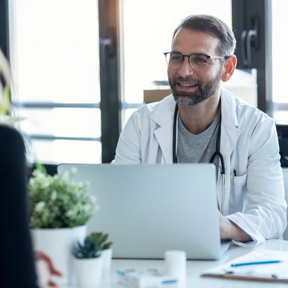 Eine Person in medizinischer Kleidung arbeitet an einem Tablet, umgeben von digitalen medizinischen Grafiken und Symbolen.