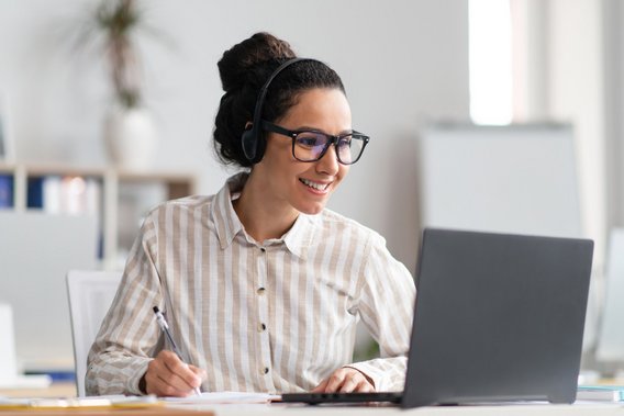 Frau mit Headset arbeitet am Laptop im Büro