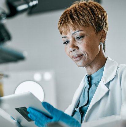 Eine Person in weißem Kittel schaut auf ein Tablet.