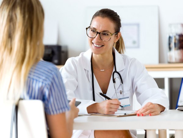 Eine Ärztin führt ein Gespräch mit einer Patientin und bietet Beratung zur Gesundheit am Arbeitsplatz