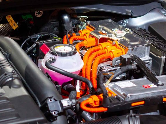 Nahaufnahme eines Hochvolt-Batteriesystems in einem Elektrofahrzeug mit orangefarbenen Kabeln und Anschlüssen.