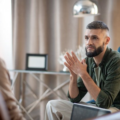 Mann in einem Gespräch, gestikuliert mit den Händen, während er eine andere Person ansieht