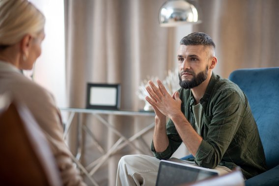 Mann in einem Gespräch, gestikuliert mit den Händen, während er eine andere Person ansieht