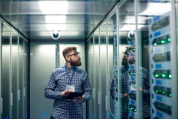 IT-Techniker mit Tablet überprüft Serverracks in einem modernen Rechenzentrum.