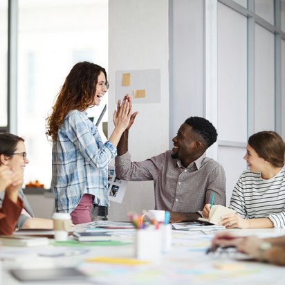 Gemeinsam Erfolge feiern im kreativen Team Team feiert gemeinsamen Erfolg mit High Five in kreativem Arbeitsumfeld