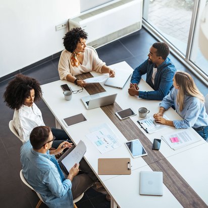 Gruppe von Menschen sitzt am Tisch bei einer beruflichen Besprechung