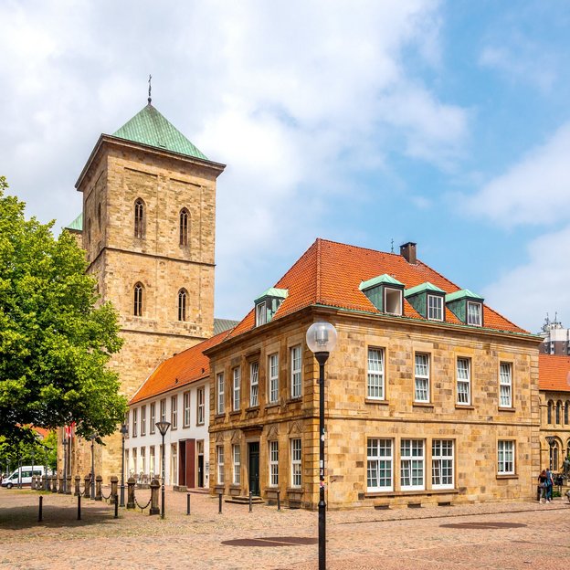 Historisches Gebäude in Osnabrück mit einem Turm und grünem Baum