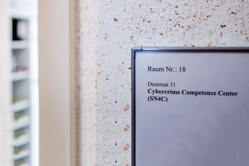 Ein Türschild mit der Aufschrift "Raum Nr.: 18, Dezernat 31, Cybercrime Competence Center (SN4C)" an einer Bürotür.