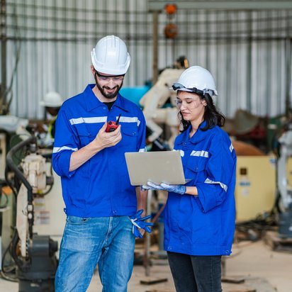 Gefährdungsbeurteilung nach ASiG Zwei Fachleute arbeiten in einem Werk und führen eine Gefährdungsbeurteilung mit Laptop und Kommunikationsgerät durch
