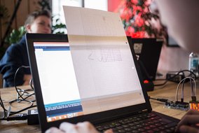 Ein Laptop mit einem Raster-Papier, auf dem etwas skizziert wurde, und eine elektronische Komponente mit LED-Matrix daneben.