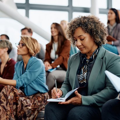 Teilnahmebedingungen der TÜV NORD Akademie im Überblick Frau macht sich Notizen während einer Schulung – symbolisiert Aufmerksamkeit und Verständnis der Teilnahmebedingungen