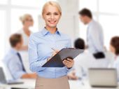 smiling businesswoman with clipboard and pen