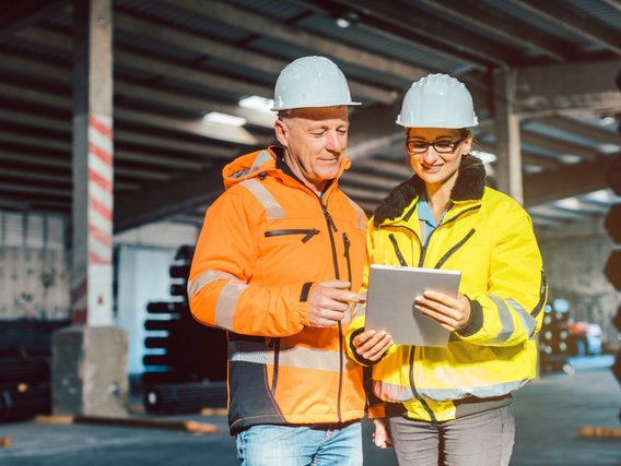 Arbeiter in Schutzanzügen und Helmen überprüfen das Inventar eines Warenlagers