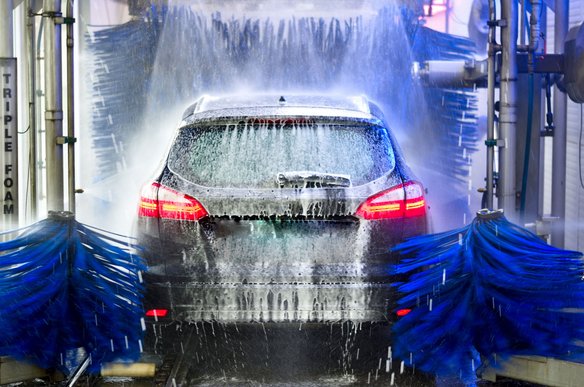 Auto in einer automatischen Autowaschanlage mit Schaum und Bürsten
