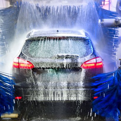 Auto in einer automatischen Autowaschanlage mit Schaum und Bürsten