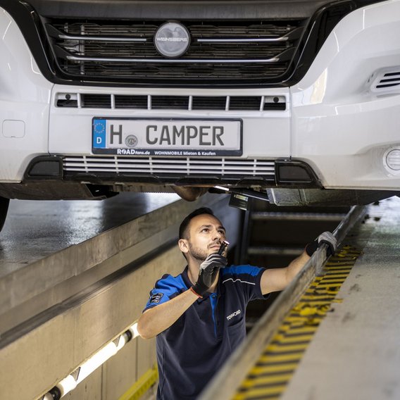 Prüfingenieur führt eine Unterbodeninspektion an einem Wohnmobil durch