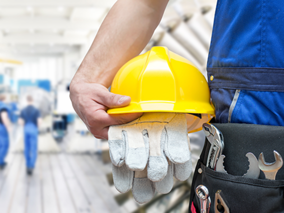 Arbeiter mit Schutzhelm, Handschuhen und Werkzeug – Symbol für Arbeitsschutz und Sicherheit im Betrieb.