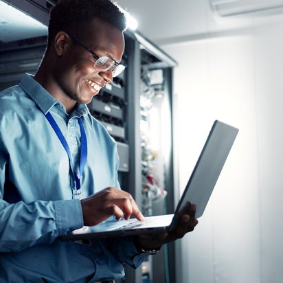 IT-Spezialist arbeitet mit Laptop im Serverraum und prüft Netzwerksysteme