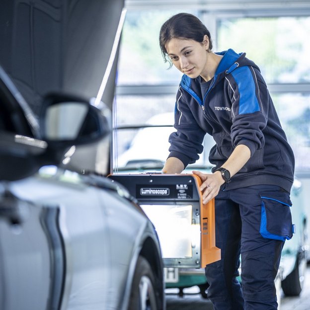 TÜV NORD Mitarbeiterin führt einen Lichttest bei einem Fahrzeug durch