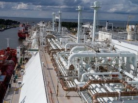 Die Deckansicht eines Tankschiffs mit komplexen Rohrleitungssystemen und Ventilen. Im Hintergrund sind Wasser und ein weiteres Schiff zu sehen.