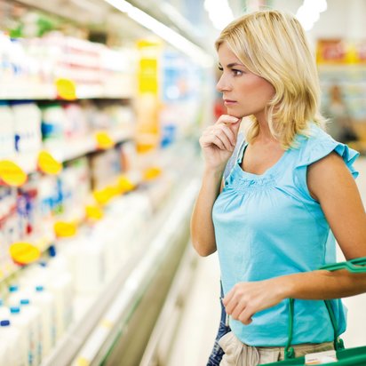 Frau steht vor Regal mit Haushaltsreinigern im Supermarkt
