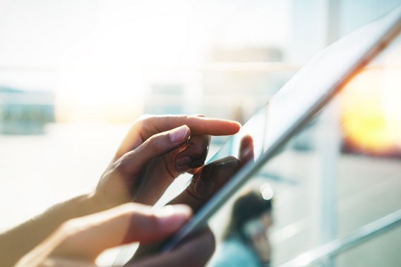 Finger bedienen ein Tablet in hellem Licht mit unscharfem Hintergrund.