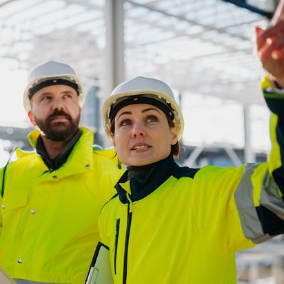 Zwei Personen in Schutzkleidung stehen in einer Lagerhalle
