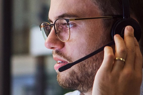 Mann mit Headset Ein Mann blickt zur Seite während er an das Headset fass, mit dem er gerade telefoniert.