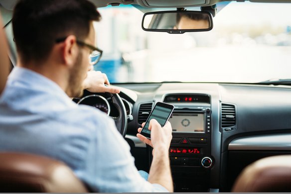 Fahrer nutzt Smartphone für digitale Unterstützung im Auto